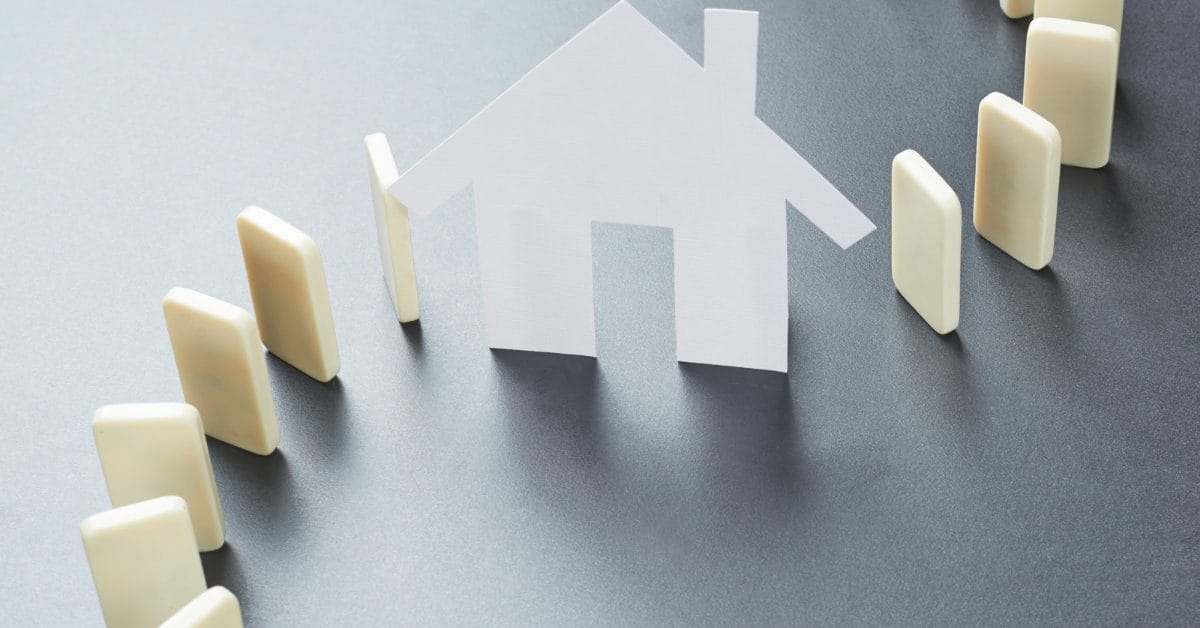 Paper house surrounded by blank dominos on a desk in a swirling pattern