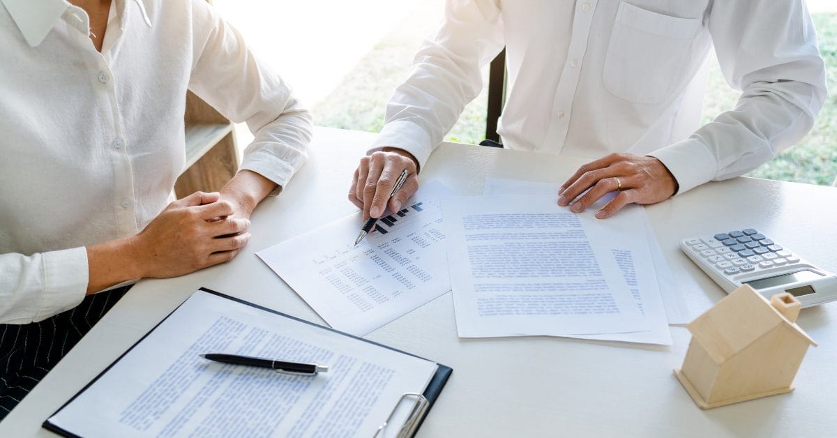 two professionals sitting at desk together looking over documents