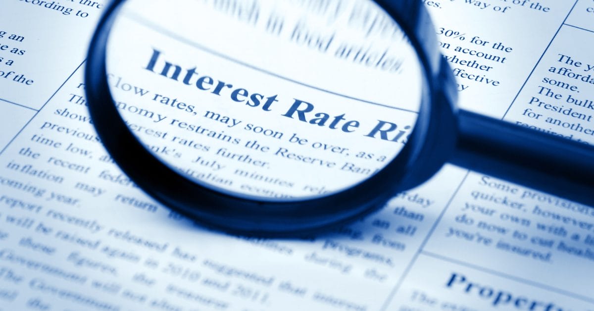 magnifying glass looking at "interest rates rise" in newspaper
