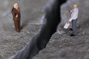 two businessmen in a standoff separated by a crevasse