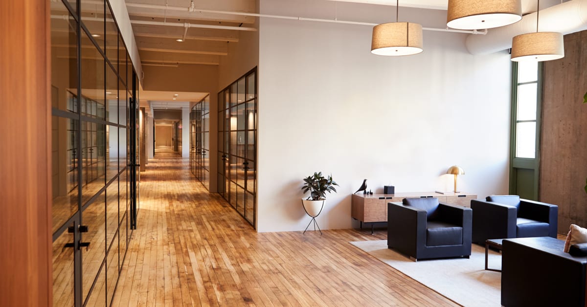 Hallway of glass offices and conference rooms with seating area in high-end office building