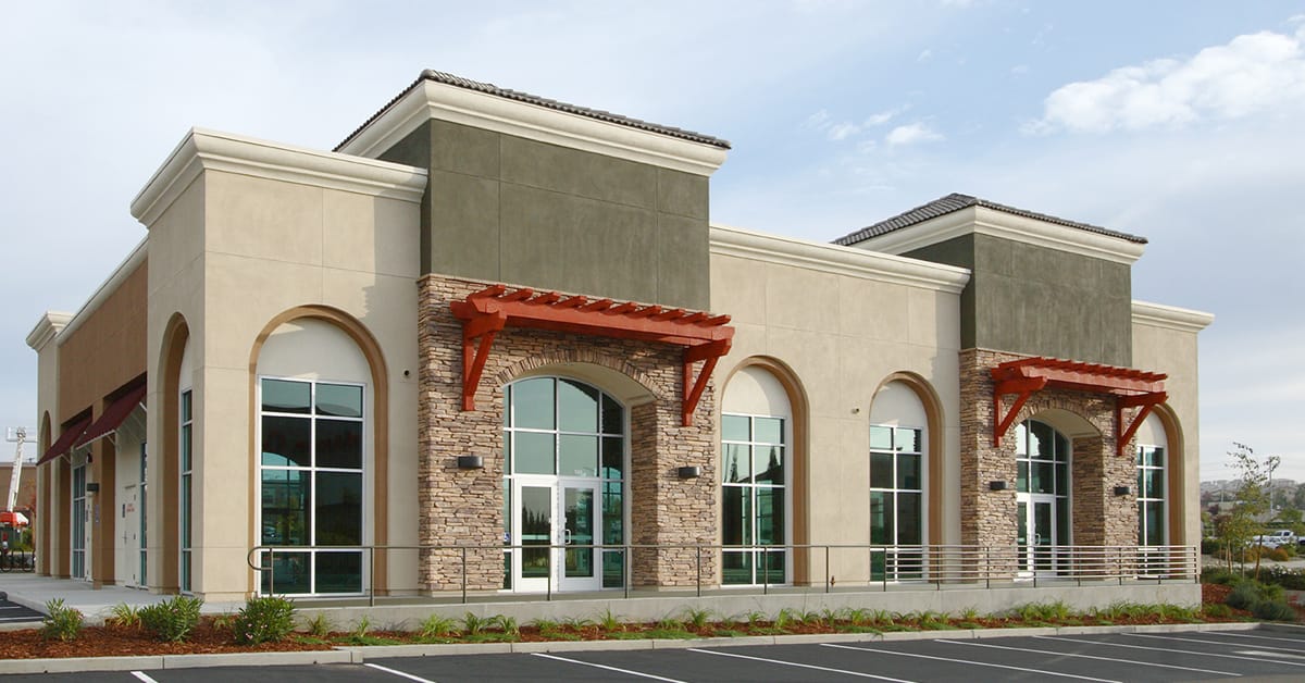 tan and green retail building with two suites