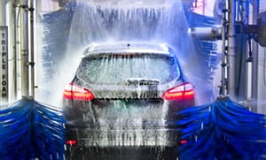 Photo of brushes and water spraying on a car in a drive thru car wash