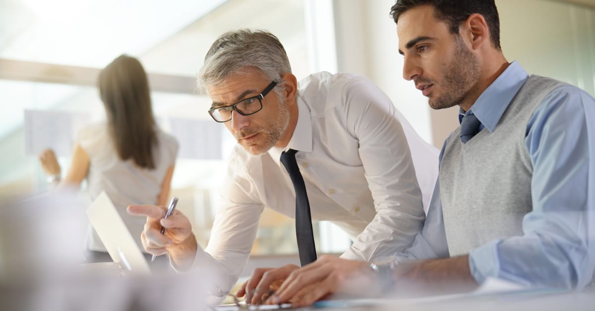 Seasoned professional working with a young professional showing him the ropes